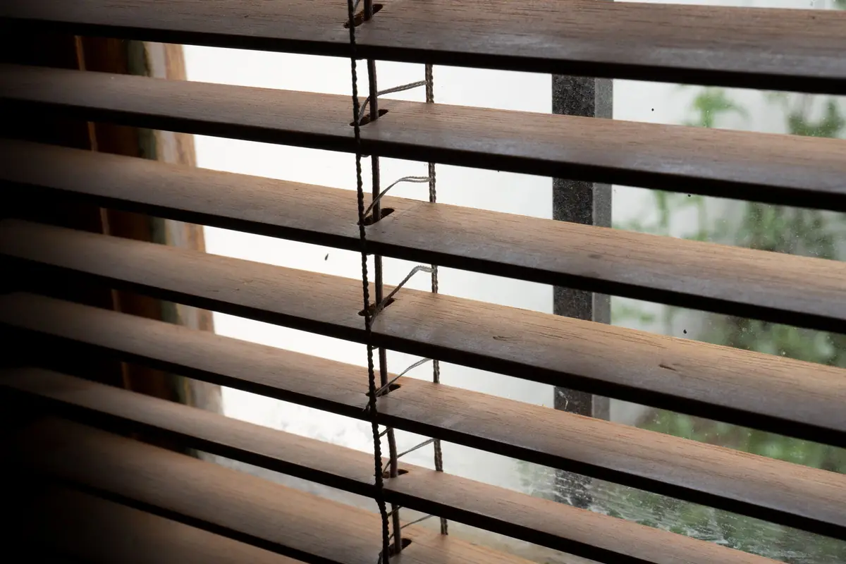Close view of horizontal wooden blind slats angled to let in soft light
