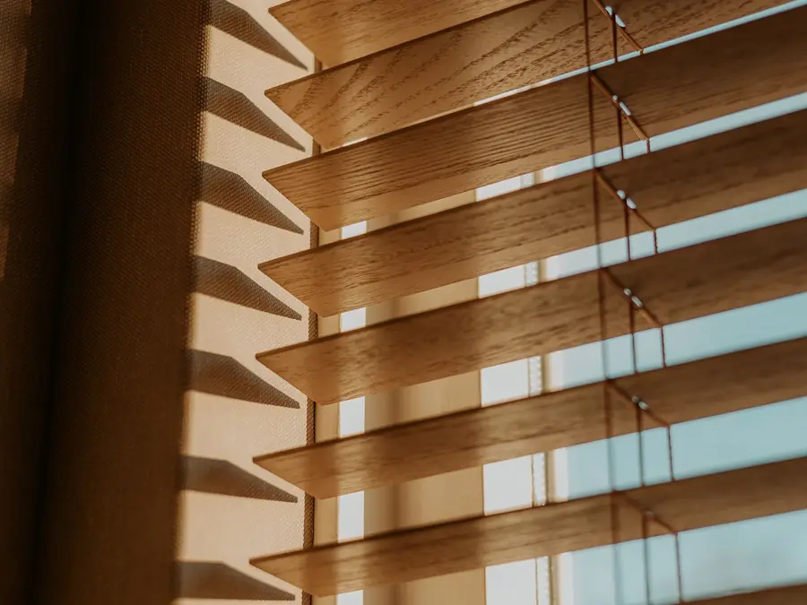 Wooden venetian blinds with warm daylight passing between the slats